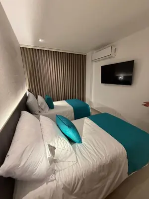 a hotel room with two beds with blue pillows at Luxy 2BR at paradise Oasis, 18 min from walled city in Cartagena de Indias