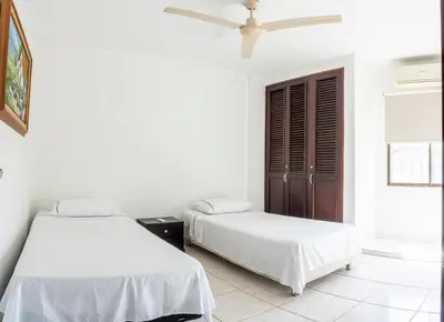 two beds in a room with white walls at Casa en conjunto cerrado, frente al mar in Santa Marta