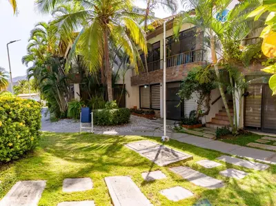 a house with palm trees in front of it at Casa en conjunto cerrado, frente al mar in Santa Marta