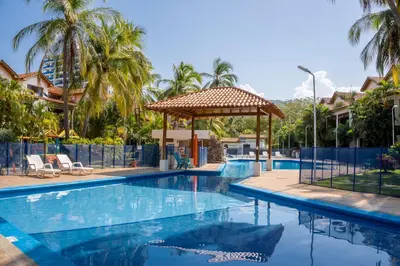 a swimming pool with a gazebo and palm trees at Casa en conjunto cerrado, frente al mar in Santa Marta