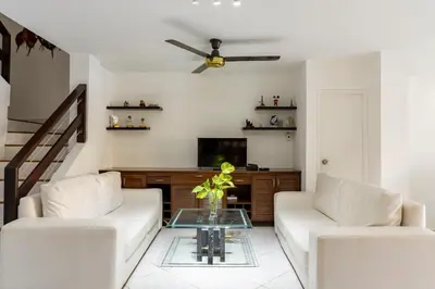 a living room with two white couches and a tv at Casa en conjunto cerrado, frente al mar in Santa Marta