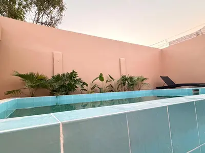 a swimming pool in front of a pink wall with plants at Casa Mercedes Cartagena in Cartagena de Indias