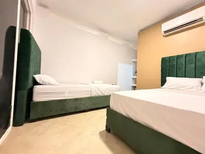 a bedroom with two beds and a green headboard at Casa Mercedes Cartagena in Cartagena de Indias