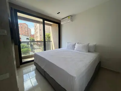a bedroom with a white bed and a large window at Habitación Edificio Shanty 203 in Barranquilla