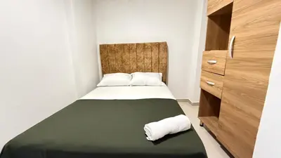 a small bedroom with a bed with a green blanket at apartamento cercano a la playa de Marbella Canapote in Cartagena de Indias