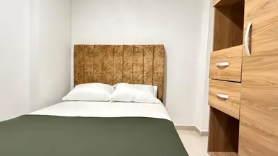 a small bedroom with a bed and a wooden headboard at apartamento cercano a la playa de Marbella Canapote in Cartagena de Indias
