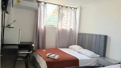 a bedroom with a bed with a desk and a window at Hotel Avanty Barranquilla in Barranquilla