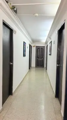 a hallway with black doors and white walls and tile floors at Hotel Avanty Barranquilla in Barranquilla