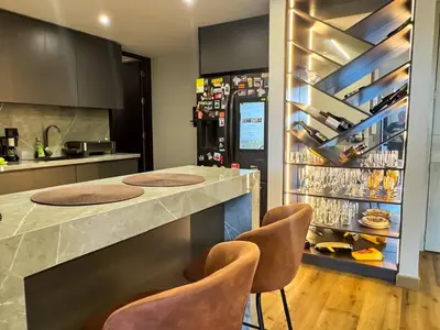 a kitchen with a bar with chairs and a refrigerator at Tu Refugio Perfecto en el Norte de Barranquilla - Cómodo, Moderno y Central in Barranquilla
