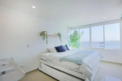 a white bedroom with a bed and a window at Riviera Loft - Apartamento con vista al mar in Cartagena de Indias