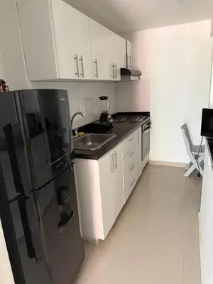 a kitchen with a black refrigerator and white cabinets at Bello Apartamento in Barranquilla