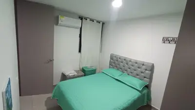 a bedroom with a bed with a green bedspread at Apartamento Hermoso in Barranquilla