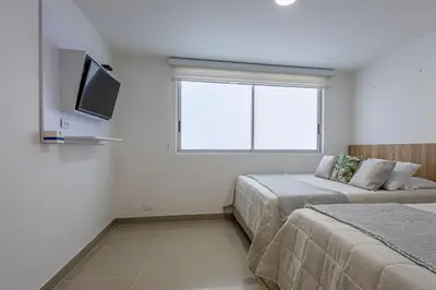 a bedroom with two beds and a tv and a window at Bocagrande Summer Beach - Primera linea de mar in Cartagena de Indias