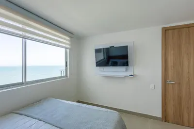 a bedroom with a bed and a tv on the wall at Bocagrande Summer Beach - Primera linea de mar in Cartagena de Indias
