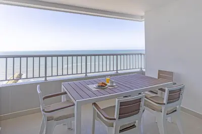 a table with chairs and a plate of food on a balcony at Bocagrande Summer Beach - Primera linea de mar in Cartagena de Indias