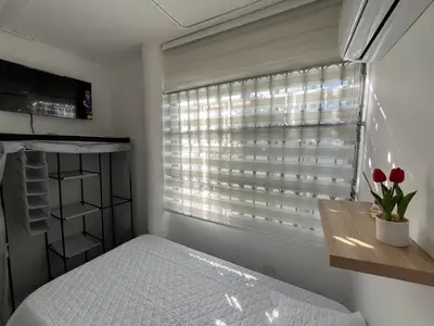a bedroom with a bed and a window with red tulips at Habitación con baño privado cerca del carnaval de Barranquilla in Barranquilla