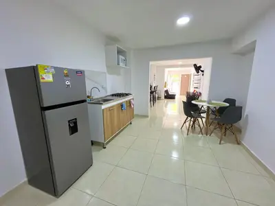 a kitchen with a refrigerator and a table with chairs at Habitación con baño privado cerca del carnaval de Barranquilla in Barranquilla