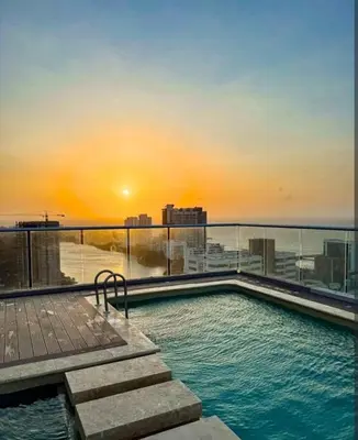 a swimming pool on top of a building with the sunset at Apartamento en cartagena vista al mar in Cartagena de Indias