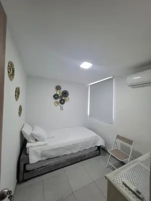 a white room with a bed and a chair at Apartamento en cartagena vista al mar in Cartagena de Indias