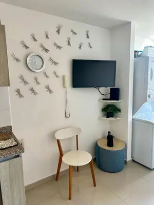 a room with a chair and a clock on a wall at Confort y Estilo en el Norte de Barranquilla in Barranquilla