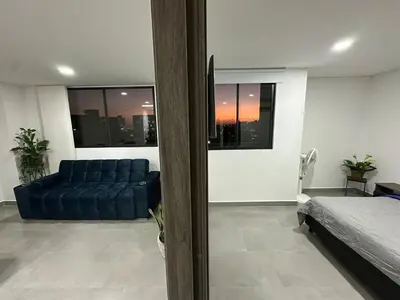 a living room with a blue couch and a bed at Beautiful, apartment near CC Único, Estadio R Martinez in Barranquilla