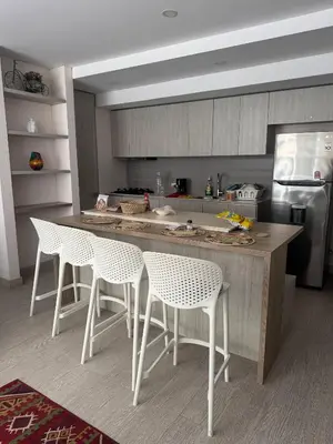 a kitchen with white chairs and a counter in a kitchen at Cartagena Cielo Mar Apartment Steps from the Beach in Cartagena de Indias