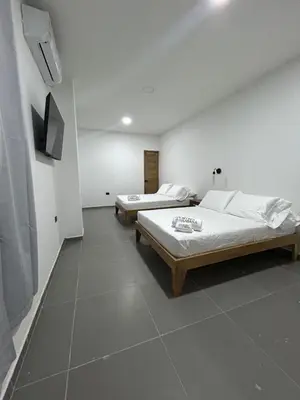 two beds in a room with white walls and tile floors at Hotel Porton De La Sabana in San Onofre