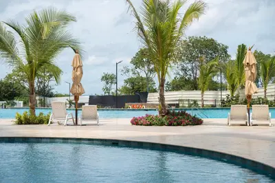 a swimming pool with chairs and umbrellas and palm trees at Loft Premium con Vista al Mar in Santa Marta