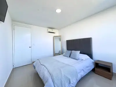 a bedroom with a large bed with a wooden headboard at Apartamento con vista al mar - Riviera Mulata Beach in Cartagena de Indias