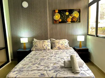 a bedroom with a bed with two lamps and a painting at Apartamento Sol y mar Cartagena in Cartagena de Indias