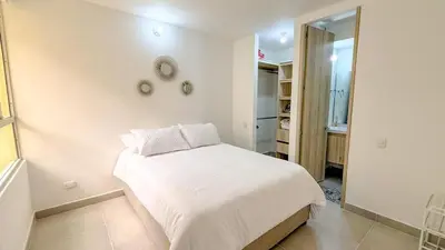 a white bedroom with a bed and a mirror at Apartamento moderno cerca del mar - Cartagena in Cartagena de Indias