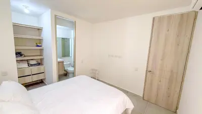 a bedroom with a white bed and a large mirror at Apartamento moderno cerca del mar - Cartagena in Cartagena de Indias