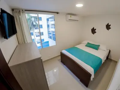 a small bedroom with a bed and a window at Marea Laguito Apartamentos Cartagena in Cartagena de Indias