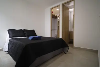 a bedroom with a black bed with a blue towel on it at Praseo in Serena del Mar