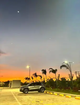 a black car parked in a parking lot with palm trees at Praseo in Serena del Mar