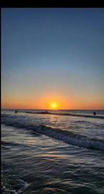a sunset over the ocean with people in the water at Praseo in Serena del Mar