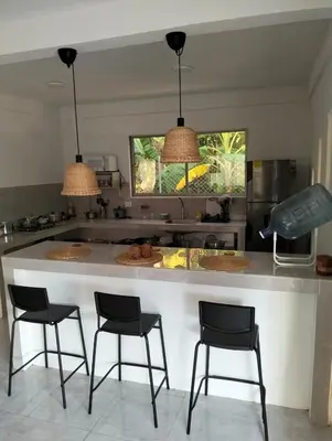 a kitchen with a large white island with four chairs at Sandymar in San Bernardo del Viento