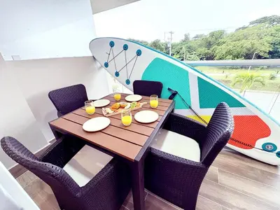 a dining table with chairs and a surfboard on the wall at Exclusivo Apartamento en Cartagena, Baia Kristal, Zona Kabo in Cartagena de Indias