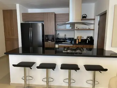a kitchen with a black counter top with bar stools at Luxury Apartment in Great Area! in Barranquilla
