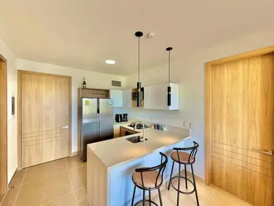 a kitchen with a sink and two bar stools at kristal lagoon view apartement in Cartagena de Indias