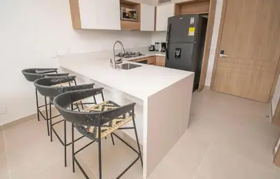 a kitchen with a counter with stools and a refrigerator at Exclusivo Apartamento en Baia Kristal, Kabo 2 in Cartagena de Indias