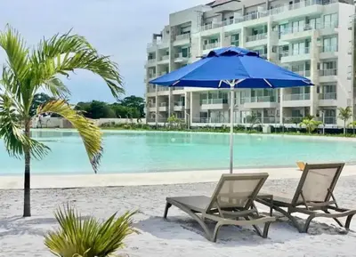a couple of chairs and an umbrella on the beach at Exclusivo Apartamento en Baia Kristal, Kabo 2 in Cartagena de Indias