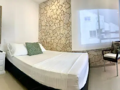 a bed in a room with a window and a chair at Amoblados Cartagena, El Laguito in Cartagena de Indias