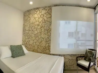 a bedroom with a bed and a window and a chair at Amoblados Cartagena, El Laguito in Cartagena de Indias