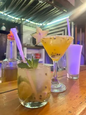 three cocktails sitting on a wooden table at Wonderland Cartagena in Cartagena de Indias