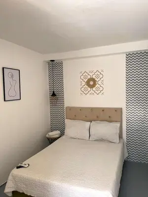 a small bedroom with a bed with white sheets at Wonderland Cartagena in Cartagena de Indias