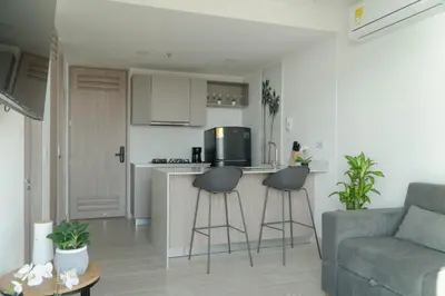 a living room with a couch and a kitchen with stools at Loft Privado , Sunset y armonia in Santa Marta