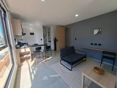 a living room with a chair and a table and a kitchen at Edificio Shanty- Easy Rents Sas in Barranquilla