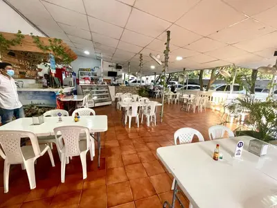 a restaurant with white tables and white chairs at Hotel Y Restaurante La Quinta in Cartagena de Indias