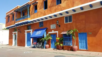 an orange building with blue doors and plants on a street at Apto exclusivo Centro Historico in Cartagena de Indias